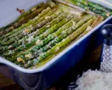 Asparagi al forno dorati e saporiti, conditi con formaggio grattugiato e pepe nero, pronti per essere gustati.