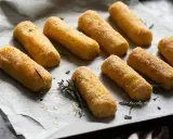 Crocchette di patate al forno dorate e croccanti, pronte per essere gustate. Profumate con rosmarino fresco.