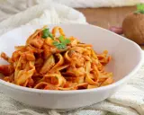 Un piatto invitante di tagliatelle ai funghi, condite con una ricca salsa al pomodoro e guarnite con prezzemolo fresco.