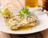 Delizioso pesce spada al forno, condito con erbe aromatiche e servito con spicchi di lime e prezzemolo fresco.