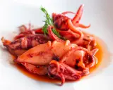 Totani in umido succulenti, cotti lentamente in un sugo saporito, guarniti con un rametto di finocchietto.
