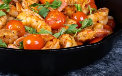 Gamberoni in padella succulenti, cotti con pomodorini e profumati aromi, pronti per essere gustati.