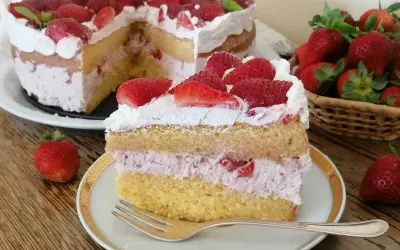 Una fetta di torta mascarpone e fragole, con strati di pan di spagna, crema rosa e fragole fresche, guarnita con panna e fragole.
