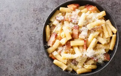 Un piatto di pasta alla zozzona fumante, con guanciale croccante e abbondante pecorino grattugiato, pronto per essere gustato.