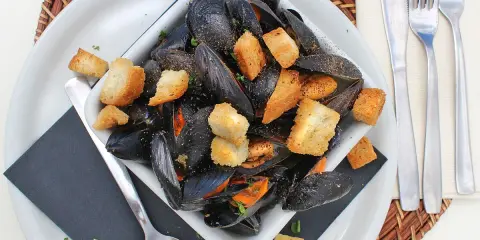 Un invitante piatto di impepata di cozze, ricco di molluschi neri e crostini dorati, pronto per essere gustato.