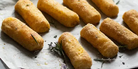 Crocchette di patate al forno dorate e croccanti, pronte per essere gustate. Profumate con rosmarino fresco.