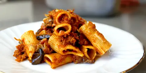 Piatto di pasta e melanzane alla napoletana, con rigatoni ricchi di sugo e melanzane fritte.