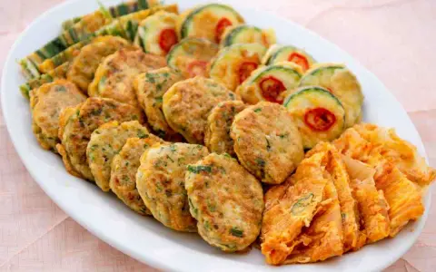 Piatto di frittelle di una volta: polpette verdi, zucchine con peperoncino e sfoglie dorate. Un tripudio di sapori e colori.