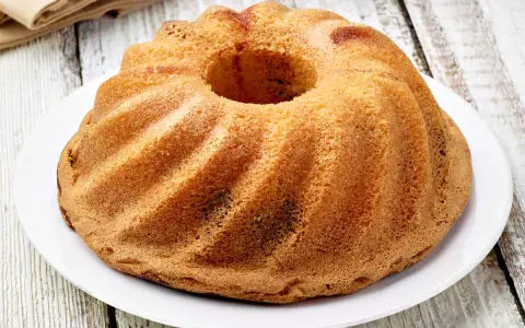 Ciambellone senza uova dorato e soffice, con la sua classica forma a ciambella, pronto per essere gustato.