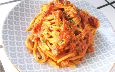 Spaghetti al tonno ricetta della nonna, un piatto gustoso e semplice, con pomodoro e tonno, guarnito con prezzemolo fresco.