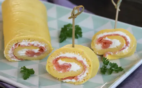 Rotolo di frittata ripieno di salmone affumicato e formaggio cremoso, guarnito con prezzemolo. Un antipasto elegante e gustoso.