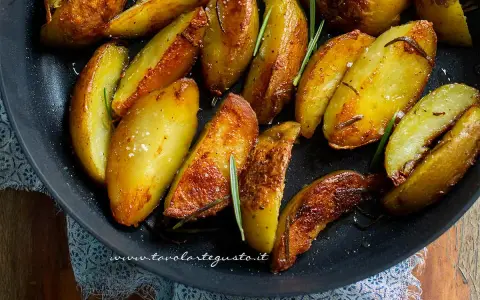 Patate in padella croccanti, dorate e profumate al rosmarino, pronte per essere gustate.
