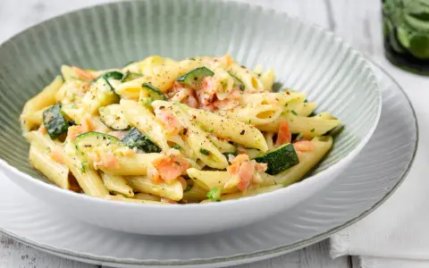 Penne con salmone e zucchine, un piatto cremoso e saporito, condito con erbe fresche e pepe nero.