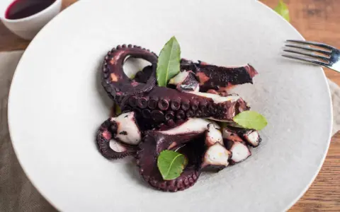 Polpo ubriaco ricetta: tentacoli succulenti e profumati, cotti a puntino e guarniti con foglie di alloro.