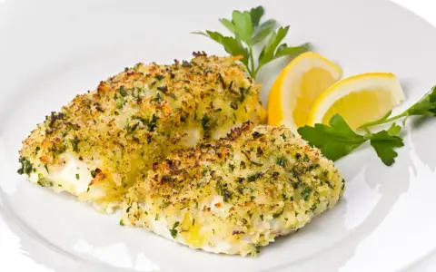 Delizioso merluzzo al forno con crosta croccante di erbe e pangrattato, guarnito con spicchi di limone e prezzemolo fresco.