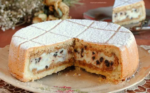 Una fetta di cassata al forno, con la sua crema vellutata e gocce di cioccolato, spolverata di zucchero a velo.