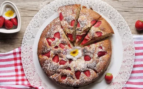 Torta di fragole e yogurt, soffice e profumata, cosparsa di zucchero a velo e decorata con un fiore. Perfetta per una colazione o merenda.