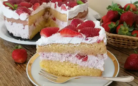 Una fetta di torta mascarpone e fragole, con strati di pan di spagna, crema rosa e fragole fresche, guarnita con panna e fragole.