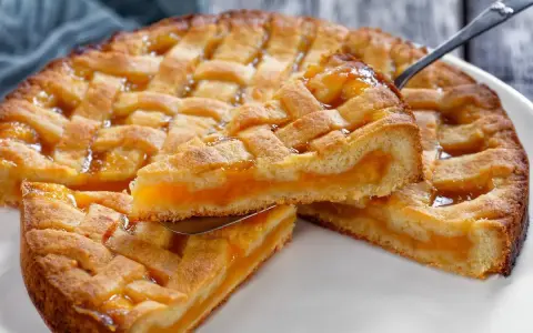 Deliziosa crostata senza glutine con ripieno di albicocche, una fetta sollevata da una paletta mostra la morbidezza.