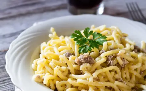Piatto di pasta con salsiccia sbriciolata, condita con un sugo cremoso e guarnita con prezzemolo fresco.