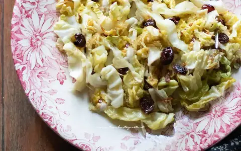 Verza in padella con uvetta, un contorno saporito e colorato servito su un piatto decorato.