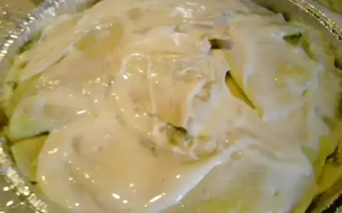 Crespelle con asparagi pronte per essere infornate, ricoperte da una cremosa besciamella.