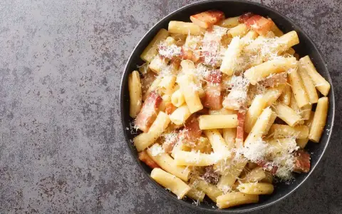 Un piatto di pasta alla zozzona fumante, con guanciale croccante e abbondante pecorino grattugiato, pronto per essere gustato.