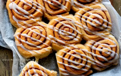 Dolci con lievito di birra, soffici girelle alla cannella con glassa bianca, pronte per essere gustate.