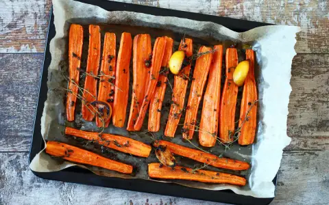 Carote al forno dorate e caramellate, condite con erbe aromatiche, pepe nero e spicchi d'aglio. Un contorno semplice e gustoso.
