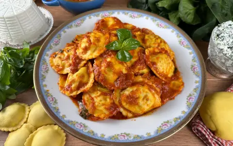 Piatto di ravioli ricotta e spinaci conditi con sugo rosso e basilico fresco. Ingredienti freschi e pasta fatta in casa.