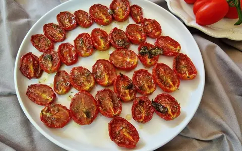 Pomodorini al forno, dorati e succosi, conditi con erbe aromatiche, pronti per insaporire ogni piatto.