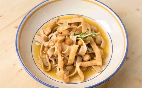 Piatto di ciceri e tria, pasta fresca con ceci e sfoglie fritte, guarnito con rosmarino.