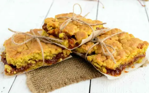 Tre fette di torta con marmellata, legate con spago, su carta da forno e tela di juta.