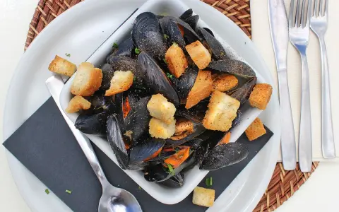 Un invitante piatto di impepata di cozze, ricco di molluschi neri e crostini dorati, pronto per essere gustato.