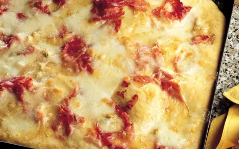 Pizza di patate filante con prosciutto croccante, un piatto invitante e gustoso.