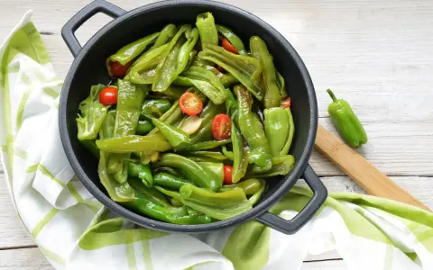 Friggitelli in padella, saltati con pomodorini e aglio, pronti per essere gustati.