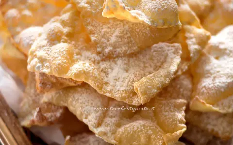 Chiacchiere croccanti, dolci e leggere, come quelle della ricetta della nonna, cosparse di zucchero a velo.