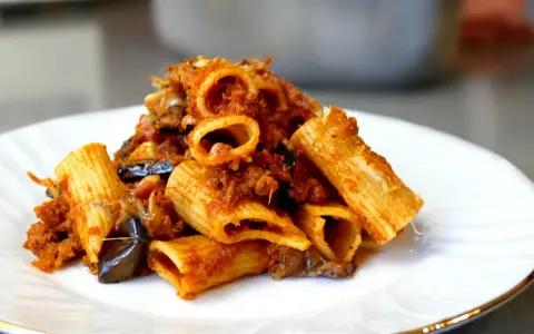 Piatto di pasta e melanzane alla napoletana, con rigatoni ricchi di sugo e melanzane fritte.