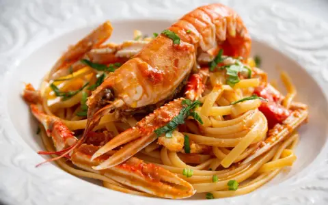 Un piatto invitante di linguine agli scampi, con pasta fresca e scampi succulenti conditi con un sugo saporito e prezzemolo tritato.