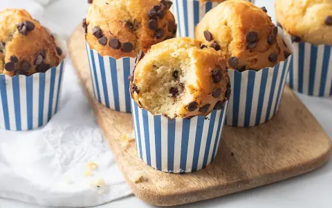 Muffin con gocce di cioccolato, perfetti per la friggitrice ad aria. Uno è stato morso, rivelando un interno soffice e goloso.