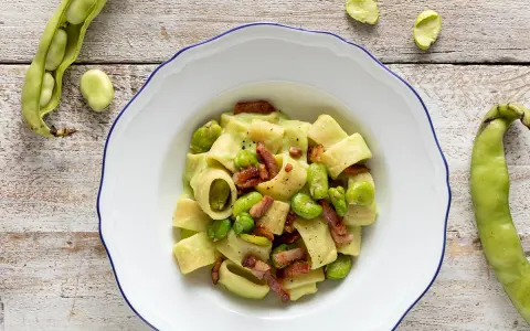 Piatto di pasta con fave fresche e croccante pancetta, un classico saporito.