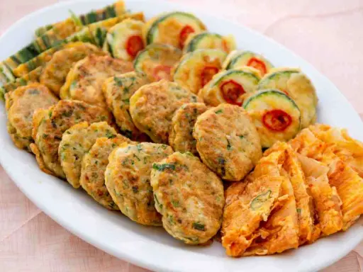 Piatto di frittelle di una volta: polpette verdi, zucchine con peperoncino e sfoglie dorate. Un tripudio di sapori e colori.