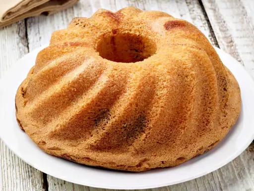 Ciambellone senza uova dorato e soffice, con la sua classica forma a ciambella, pronto per essere gustato.
