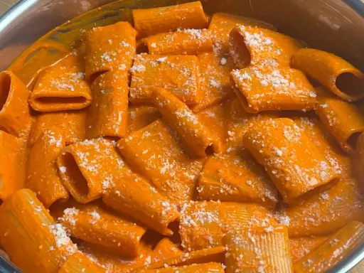 Rigatoni cremosi in salsa all'nduja, spolverati con parmigiano. Un piatto che scalda il cuore e il palato.