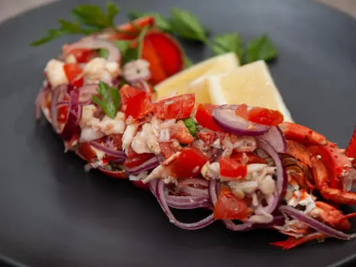 Astice alla catalana: polpa di astice sfilacciata con pomodoro, cipolla rossa e limone, guarnito con prezzemolo.