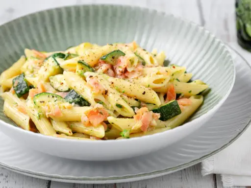 Penne con salmone e zucchine, un piatto cremoso e saporito, condito con erbe fresche e pepe nero.