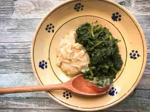 Piatto rustico con fave e cicoria, un classico della cucina italiana, servito su un piatto decorato con fiori blu.