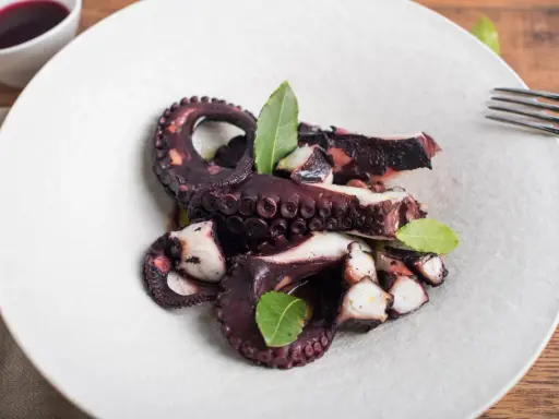 Polpo ubriaco ricetta: tentacoli succulenti e profumati, cotti a puntino e guarniti con foglie di alloro.