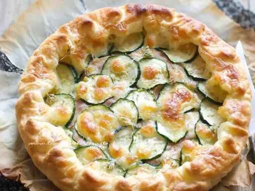 Deliziosa torta salata con zucchine, formaggio fuso e croccante pasta sfoglia. Perfetta per un pranzo leggero o un aperitivo.