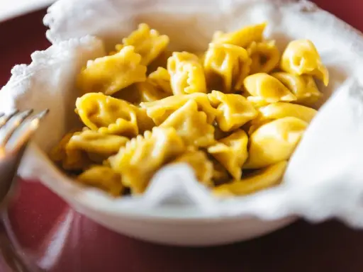 Un primo piatto invitante: tanti ravioli del plin dorati, serviti in una ciotola bordata di bianco.